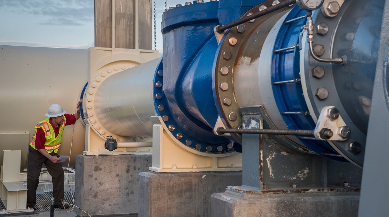 man in hard hat looking at pipes