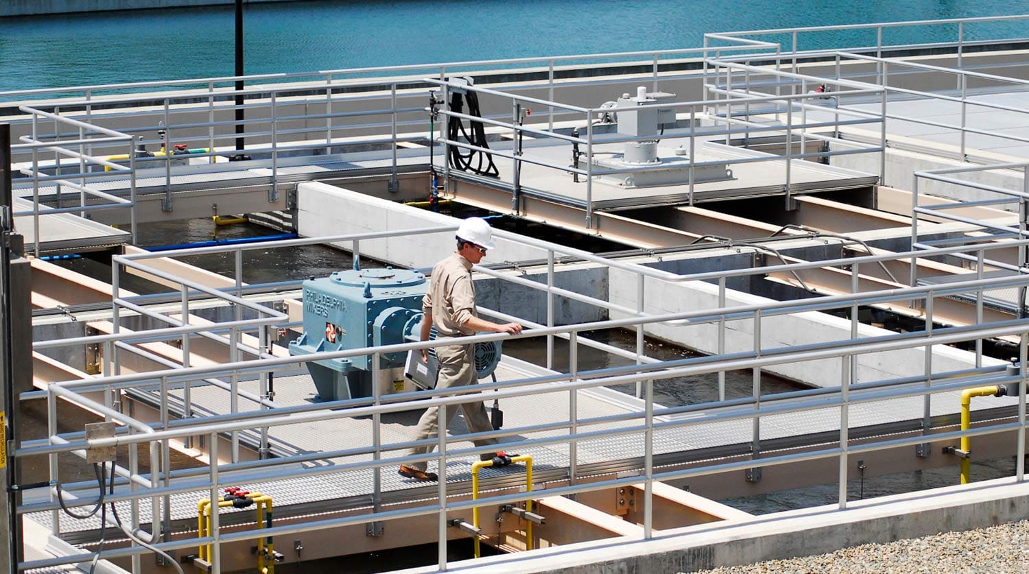 Man in hardhat walking on a catwalk in a plant