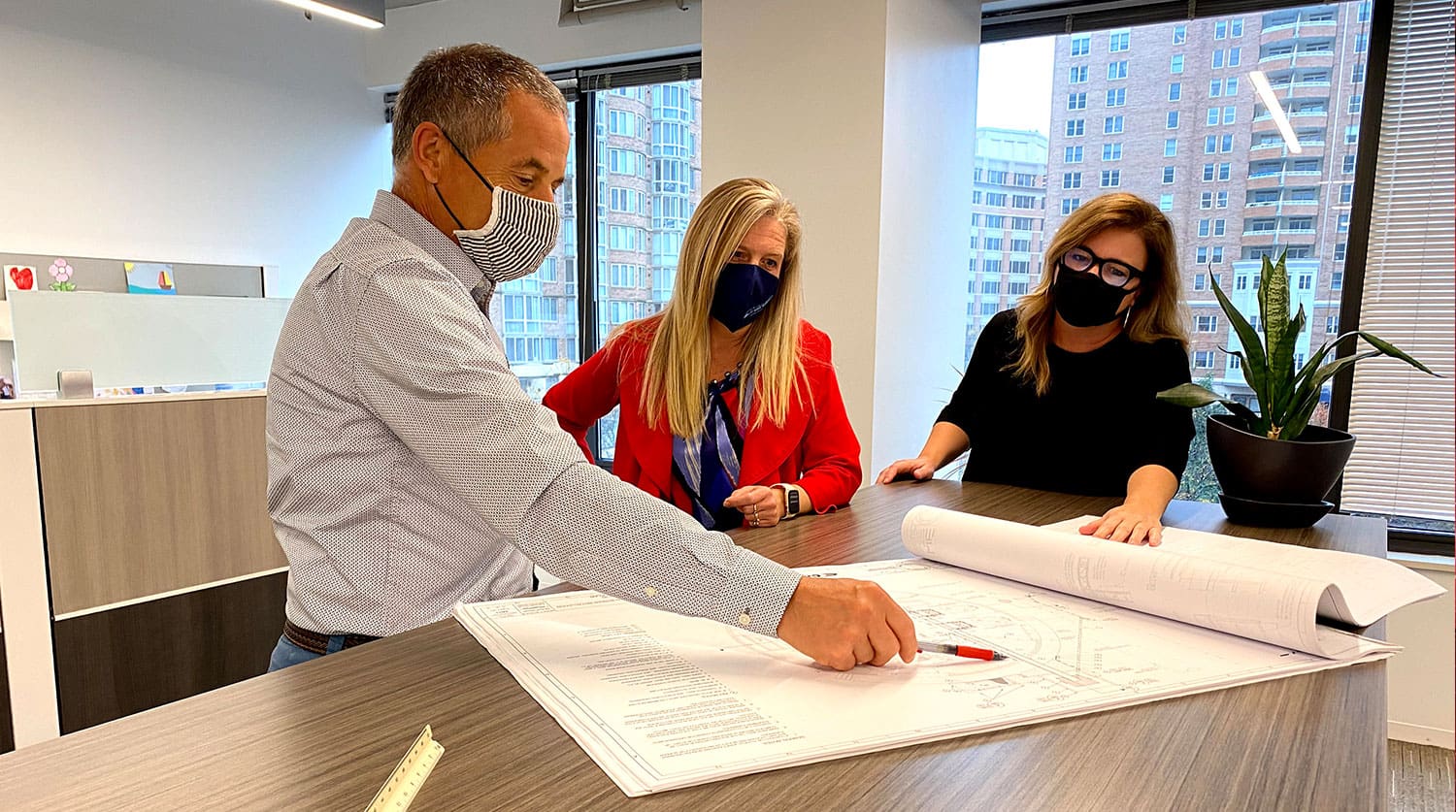 Three engineers looking at blueprints in an office
