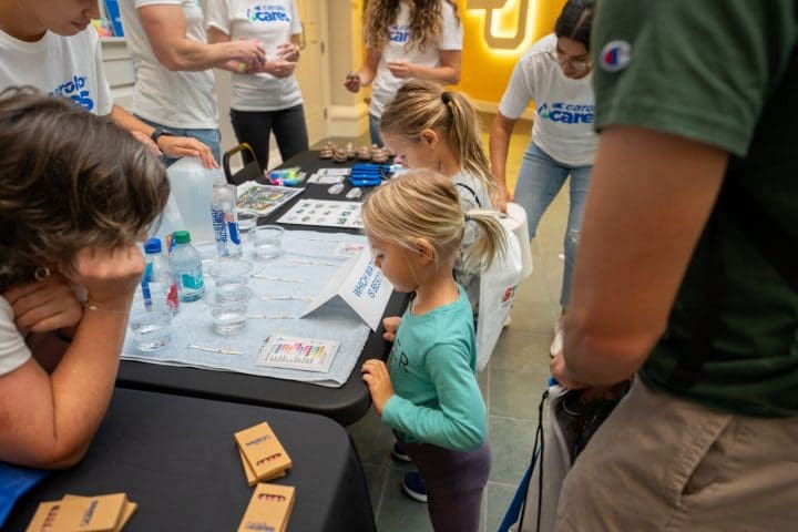 Young child practicing water experiments at a Carollo Cares event