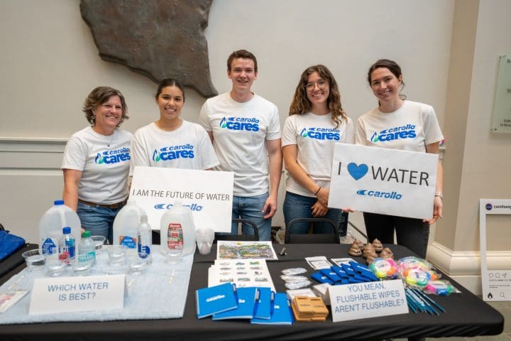 Carollo Cares employees in front of a table at a STEM festival where they taught kids about water