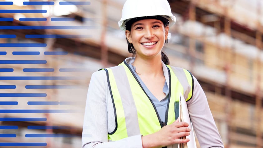 Woman in hard hat and reflector vest smiles while at work