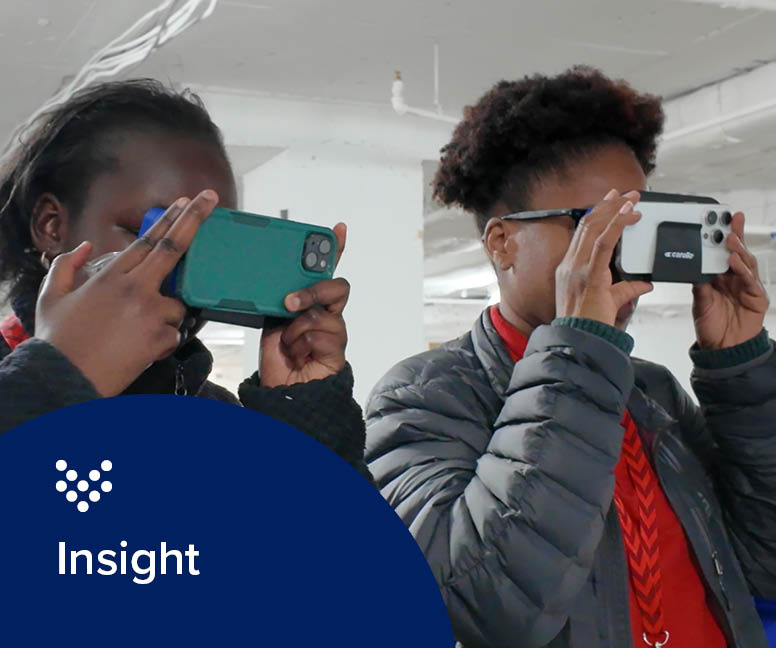 Photo of two young women looking into VR goggles at a water treatment plant as part of the 2025 National STEM Festival